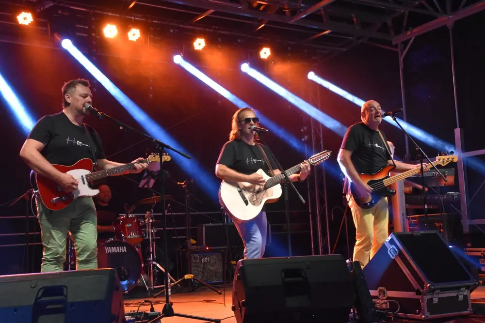 Koncert plenerowy: zespół na scenie w wiązkach światła